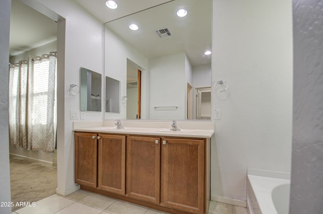 bathroom with double vanity, visible vents, a sink, a tub, and tile patterned floors