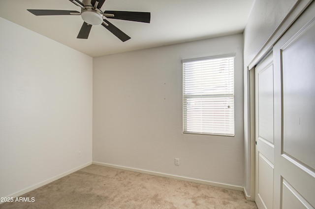 empty room with baseboards, a ceiling fan, and light colored carpet