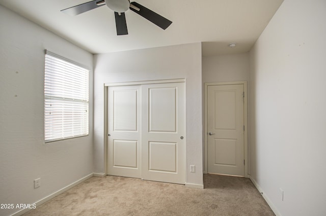 unfurnished bedroom with a ceiling fan, baseboards, a closet, and light colored carpet