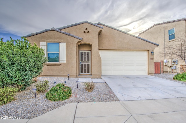 mediterranean / spanish house with concrete driveway, an attached garage, a tile roof, and stucco siding