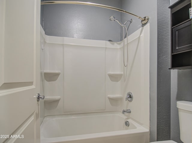 bathroom featuring a textured wall, shower / tub combination, and toilet