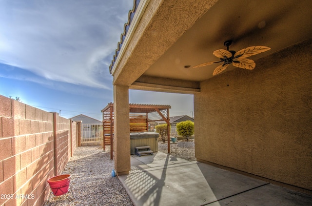 view of patio with ceiling fan, a fenced backyard, and a hot tub