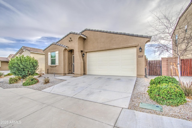 mediterranean / spanish home featuring a garage, concrete driveway, a tile roof, fence, and stucco siding