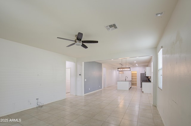 unfurnished living room featuring visible vents, a ceiling fan, light tile patterned flooring, a sink, and baseboards