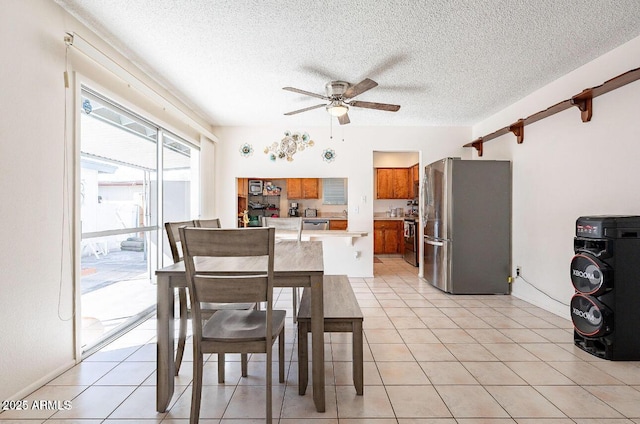 dining space featuring a ceiling fan, a textured ceiling, and light tile patterned floors