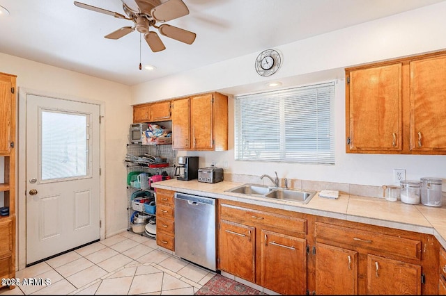 kitchen with dishwasher, a sink, light countertops, ceiling fan, and brown cabinetry