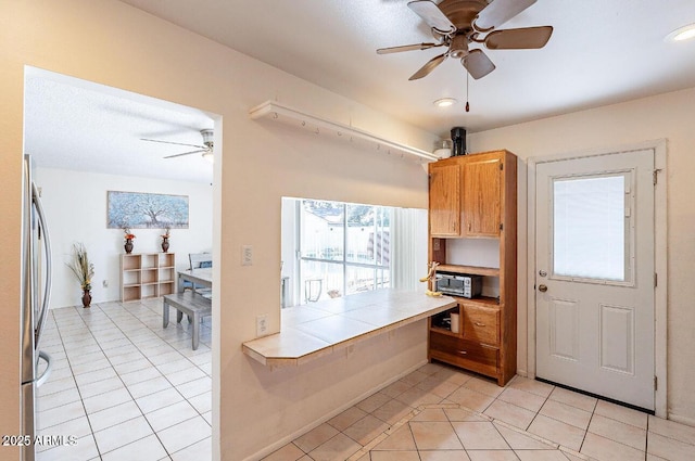 kitchen featuring ceiling fan, tile counters, light tile patterned floors, stainless steel refrigerator, and recessed lighting