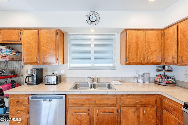 kitchen with stainless steel dishwasher, a sink, light countertops, and brown cabinetry
