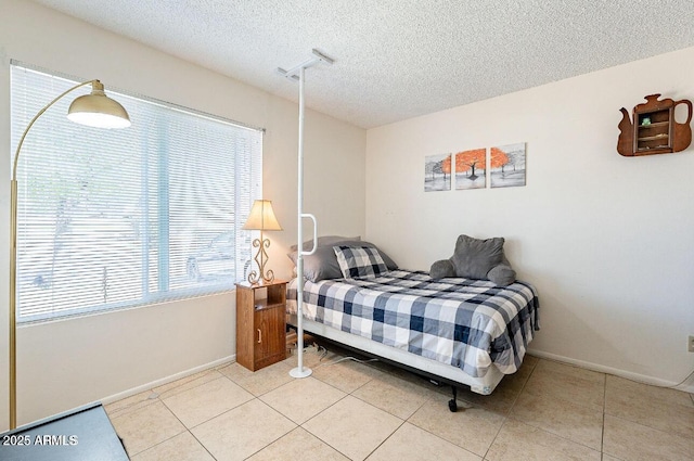 bedroom with a textured ceiling, baseboards, and light tile patterned floors