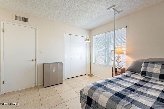 tiled bedroom featuring a textured ceiling, a closet, and baseboards