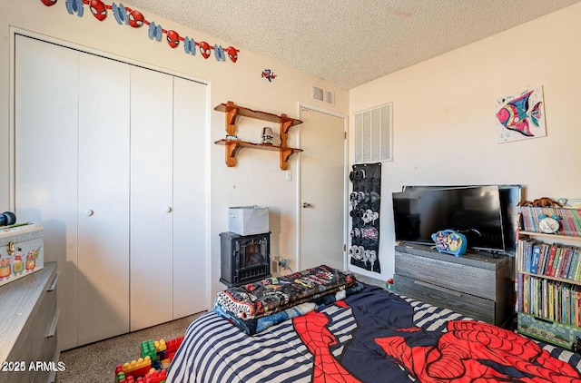 carpeted bedroom with a wood stove, a textured ceiling, and a closet