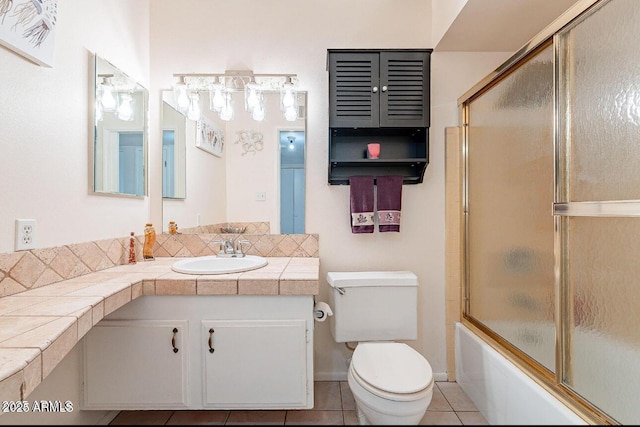 bathroom featuring tile patterned flooring, toilet, combined bath / shower with glass door, and vanity