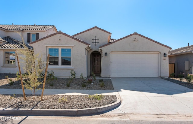 mediterranean / spanish-style house featuring a garage, concrete driveway, a tiled roof, and stucco siding