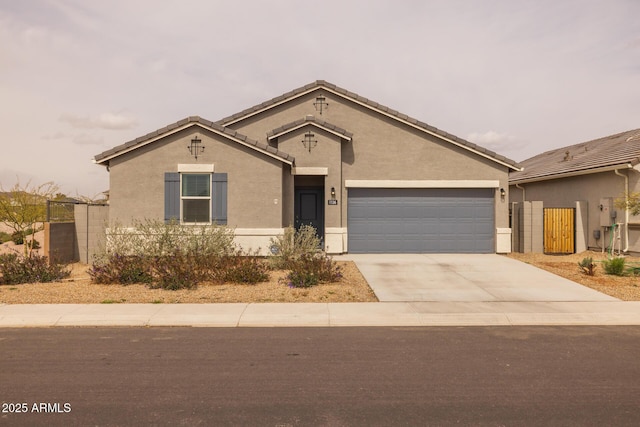 view of front of home with fence, driveway, stucco siding, a garage, and a tiled roof