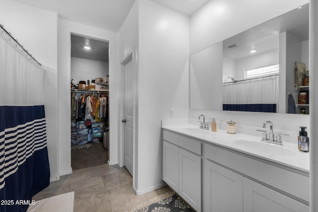 full bath featuring double vanity, tile patterned floors, a spacious closet, and a sink