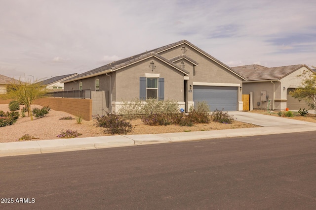 view of front of property featuring stucco siding, driveway, a garage, and fence