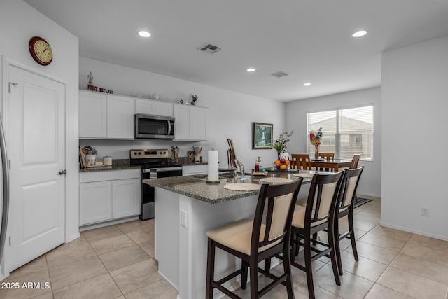 kitchen with a breakfast bar, visible vents, white cabinetry, and stainless steel appliances