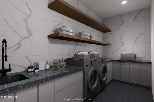 clothes washing area featuring stone wall, recessed lighting, a sink, cabinet space, and washing machine and clothes dryer