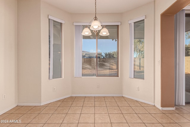 unfurnished dining area featuring a wealth of natural light, light tile patterned flooring, and a chandelier