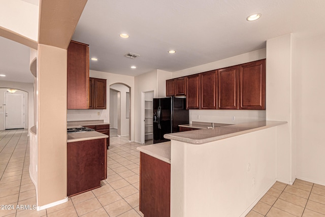 kitchen with kitchen peninsula, black refrigerator with ice dispenser, and light tile patterned floors