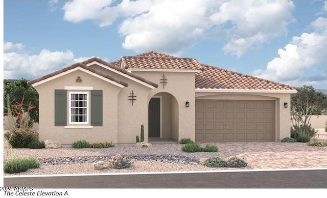 mediterranean / spanish house with a garage, decorative driveway, a tile roof, and stucco siding