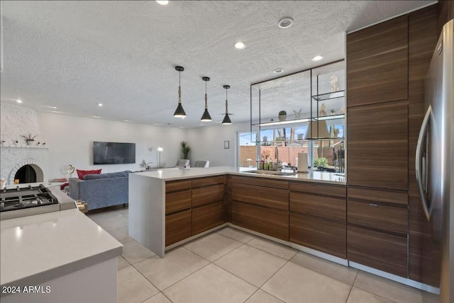 kitchen with light countertops, brown cabinetry, a brick fireplace, open floor plan, and a sink