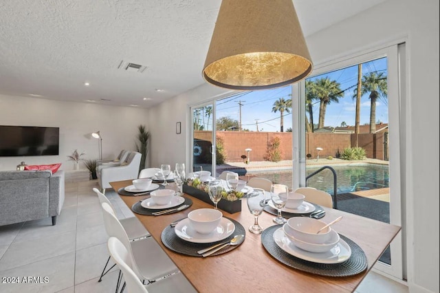 dining space featuring tile patterned flooring, visible vents, and a textured ceiling