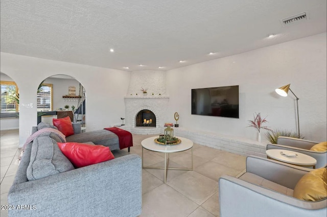 living room with visible vents, a fireplace, a textured ceiling, and tile patterned floors