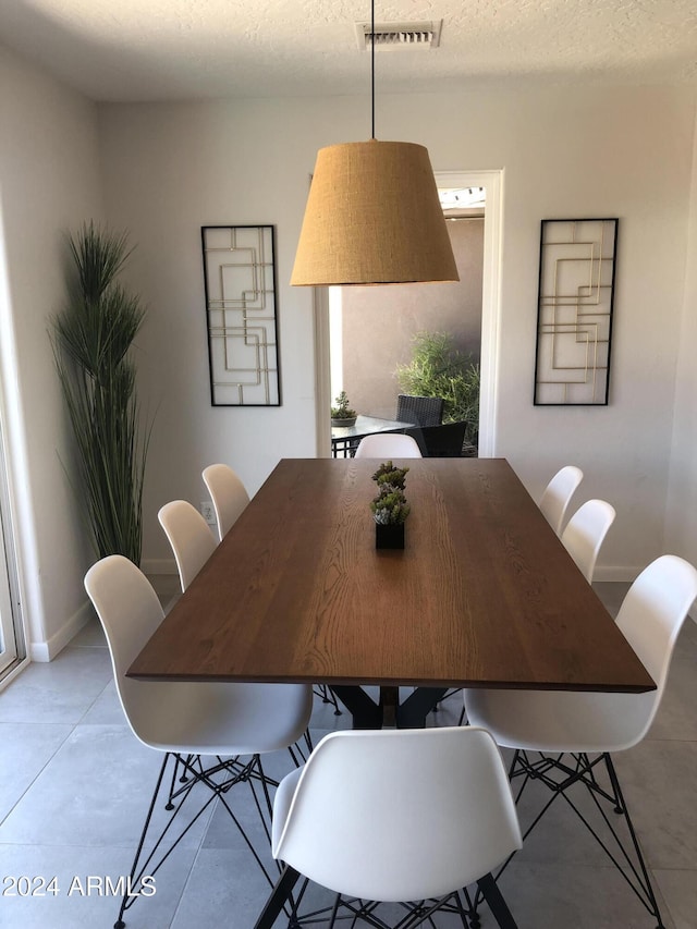 dining room featuring visible vents, a textured ceiling, and baseboards