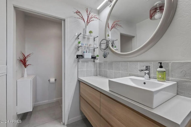 bathroom with tasteful backsplash, tile patterned flooring, vanity, and baseboards