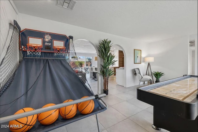 game room featuring a textured ceiling, tile patterned flooring, arched walkways, and visible vents