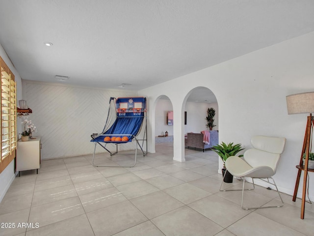 sitting room with arched walkways, visible vents, and tile patterned floors