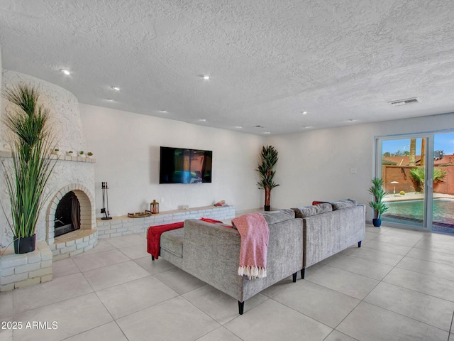 tiled living room with visible vents, a fireplace, and a textured ceiling