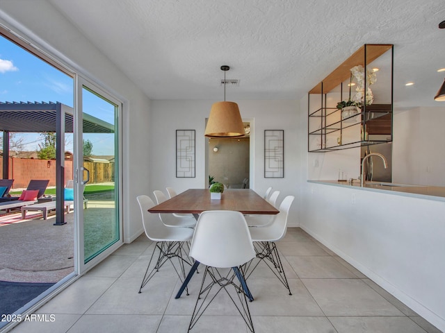 dining space with light tile patterned floors, baseboards, visible vents, and a textured ceiling
