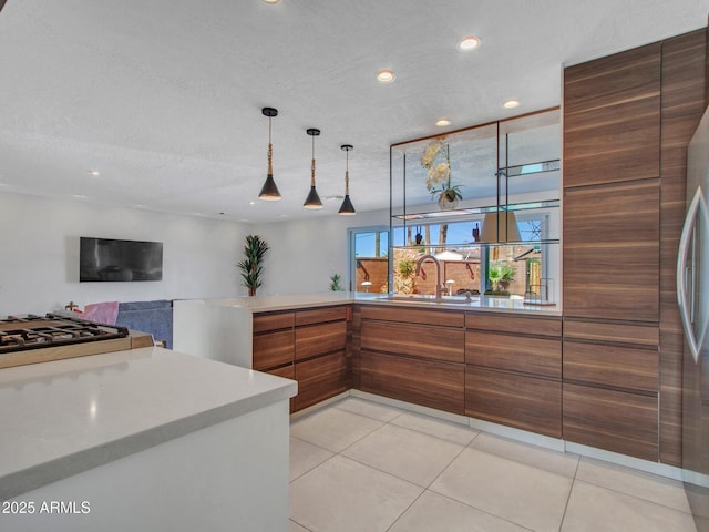 kitchen featuring brown cabinets, light countertops, light tile patterned flooring, a sink, and modern cabinets