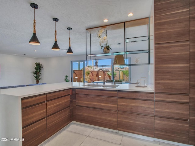 kitchen featuring brown cabinetry, light countertops, and a sink
