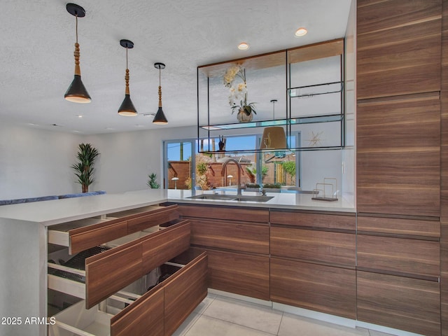 bar featuring hanging light fixtures, a textured ceiling, a sink, and light tile patterned flooring