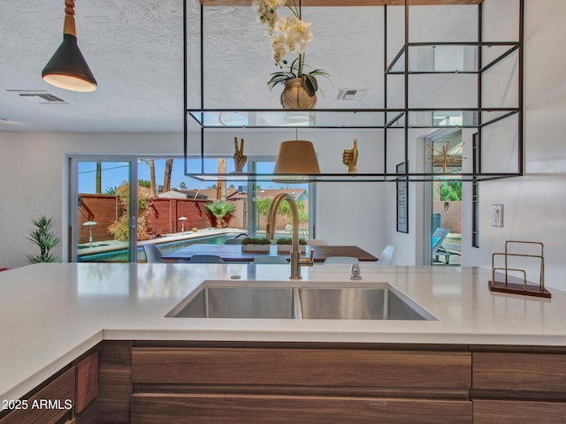 kitchen featuring a textured ceiling, light countertops, a sink, and visible vents