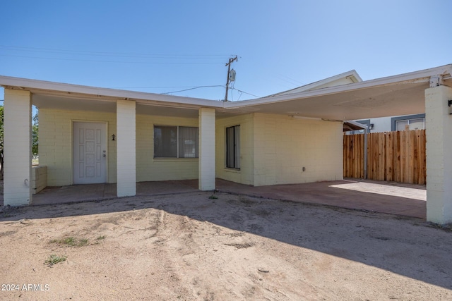 rear view of property featuring concrete block siding and fence