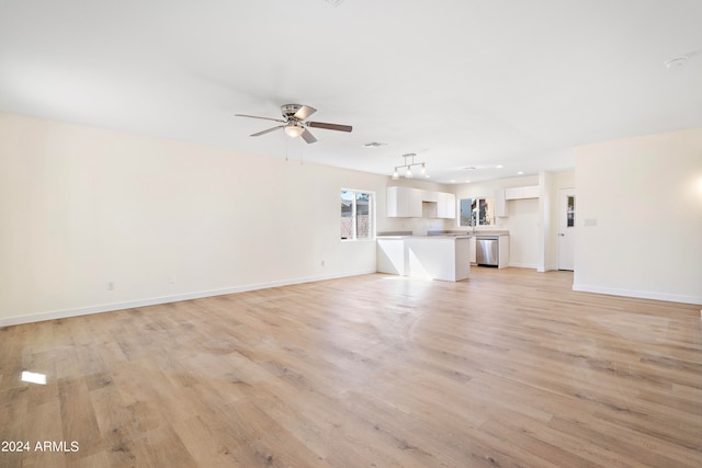 unfurnished living room featuring ceiling fan, light wood-type flooring, and sink