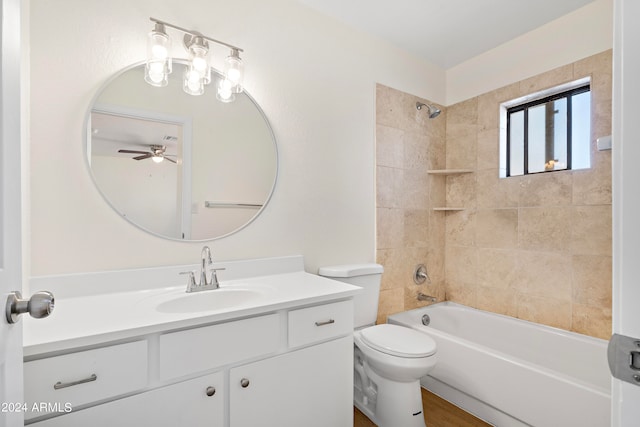 full bathroom with ceiling fan, tiled shower / bath, toilet, and vanity with extensive cabinet space