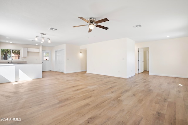 unfurnished living room with light hardwood / wood-style flooring, ceiling fan, and sink