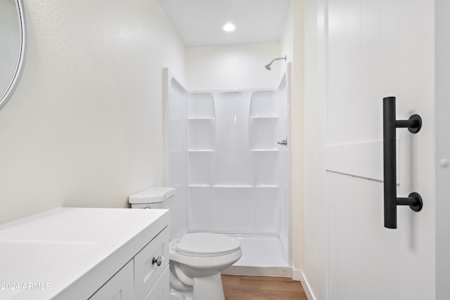 bathroom with toilet, vanity, walk in shower, and wood-type flooring