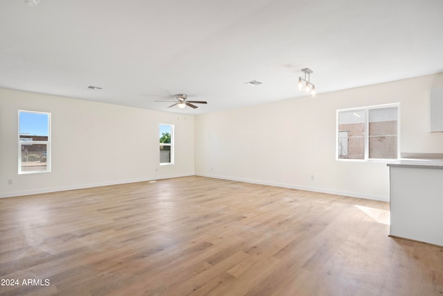 unfurnished room featuring light hardwood / wood-style floors and ceiling fan with notable chandelier