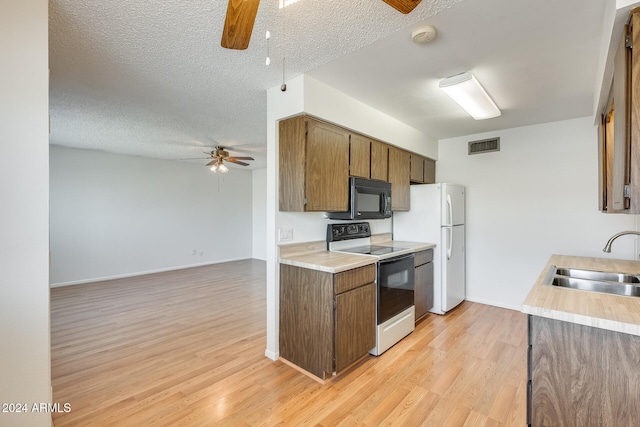 kitchen with white appliances, sink, ceiling fan, a textured ceiling, and light hardwood / wood-style floors