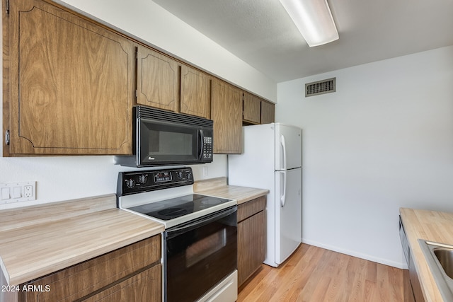 kitchen with light hardwood / wood-style floors, white appliances, and sink