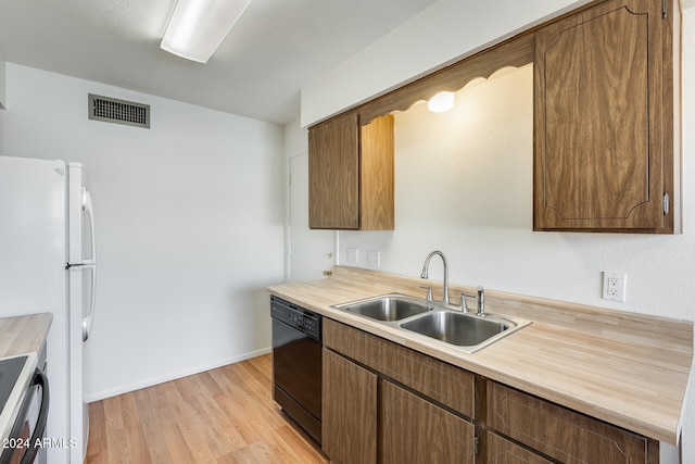 kitchen with stainless steel range, sink, white refrigerator, dishwasher, and light hardwood / wood-style floors