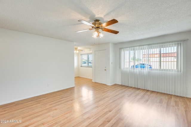 unfurnished room featuring ceiling fan, a healthy amount of sunlight, light hardwood / wood-style floors, and a textured ceiling