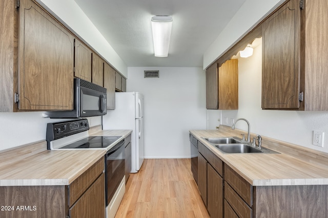 kitchen featuring sink, black appliances, and light wood-type flooring