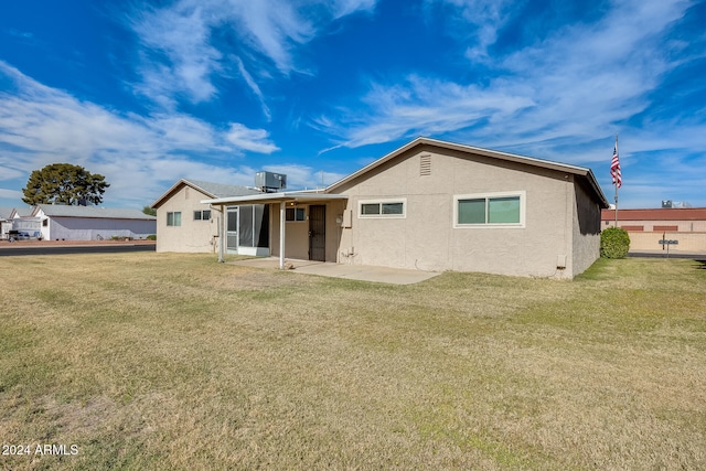 rear view of house featuring a lawn, cooling unit, and a patio area